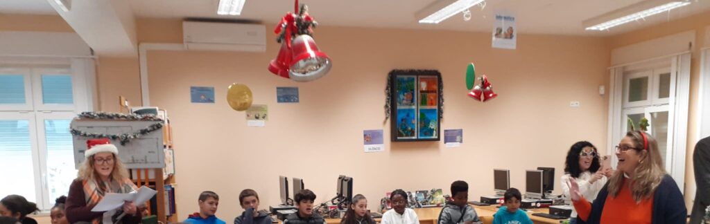 Alunos e professoras cantam na bliboteca decorada com motivos natalícios  